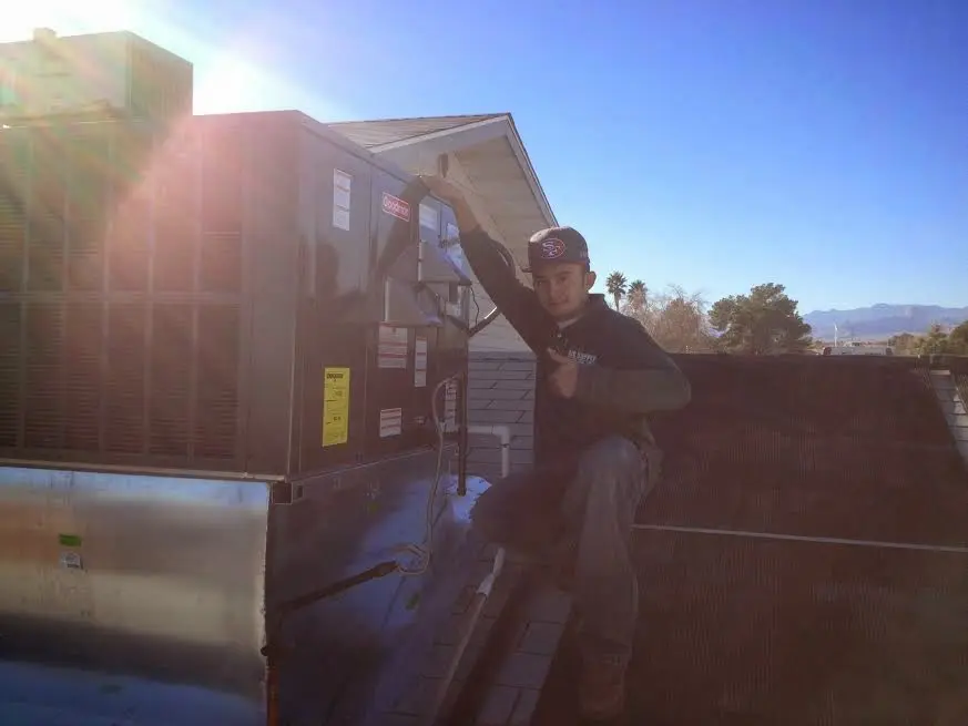 HVAC technician performing Air Duct Cleaning on a rooftop unit in Batavia