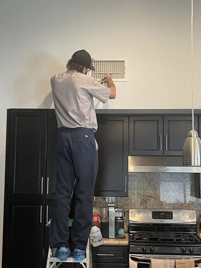 Technician inspecting an air vent during HVAC service in Batavia